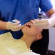 A dentist hands working on young woman patient with dental tools.
